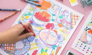 Une main colorie une scène de repas avec des pastels. Une idée art créatif pour un moment joyeux et coloré.