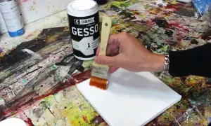 Préparation d'une toile pour peindre. On utilise un pinceau pour mélanger gesso et peinture acrylique, créant une base parfaite pour l'art.