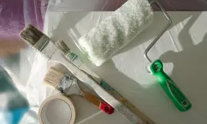 Pinceaux et rouleau de peinture acrylique prêts à nettoyer. Une bande de masquage est aussi visible.