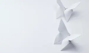 Deux papillons en origami blanc, créés avec un grammage papier origami idéal, flottent sur un fond épuré.