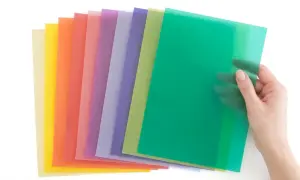 Une main tient une feuille verte translucide, révélant une pile de papiers colorés. Idéal pour faire un vitrail en papier calque.