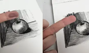 Un doigt est utilisé pour estomper un dessin au fusain d'une pomme, technique d'un artiste connu.