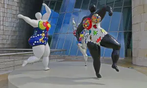 Trois sculptures colorées de Niki de Saint Phalle, des Nanass, dansent joyeusement devant le musée Guggenheim.