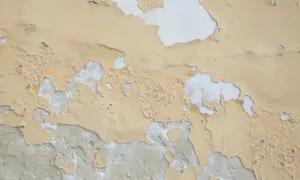 Texture d'un mur où la peinture qui ne tient pas s'écaille, révélant le plâtre blanc en dessous.