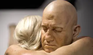 Un homme chauve aux yeux clos est étreint par une femme aux cheveux blonds. Une œuvre saisissante d'un peintre hyperréaliste français.
