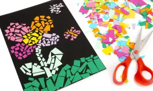 Un collage papier de soie coloré représente des fleurs sur fond noir, à côté de ciseaux et de chutes de papier.