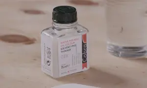 Bouteille de diluant Cobra pour peinture acrylique à base d'eau, sur fond de bois.