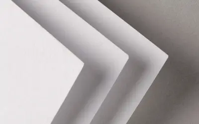 Trois feuilles de papier blanc superposées, créant un effet d'escalier. La texture du papier rappelle celle d'un **format raisin** pour une œuvre d'art.