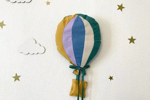 Gabarit patron montgolfière papier, cousu main, prêt à décorer une chambre d'enfant. Nuages et étoiles dorées l'accompagnent.