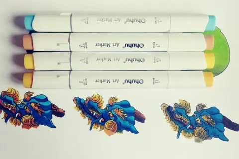 Quatre feutres à alcool Ohuhu prêts à créer un dégradé sur des dragons bleus et dorés.