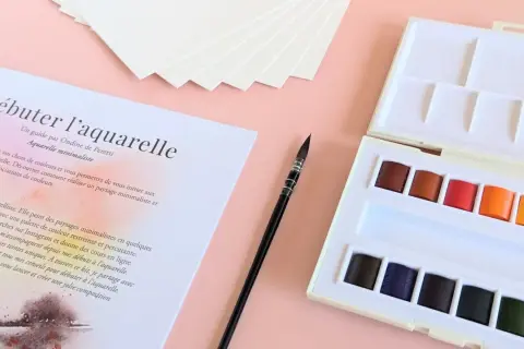 Kit de matériel peinture aquarelle : palette de couleurs vives, pinceau fin et papier texturé pour débuter.