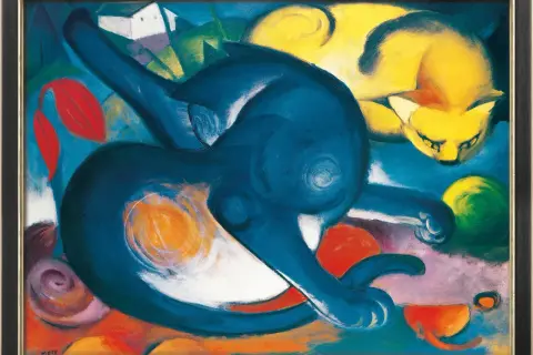 Deux chats aux couleurs vives, l'un bleu, l'autre jaune, dansent dans un paysage abstrait. Une œuvre de Franz Marc, ce "chat" exprime la joie et le mouvement.