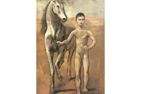 Un jeune garçon nu, comme dans un dessin Picasso enfant, pose fièrement à côté d'un cheval blanc.