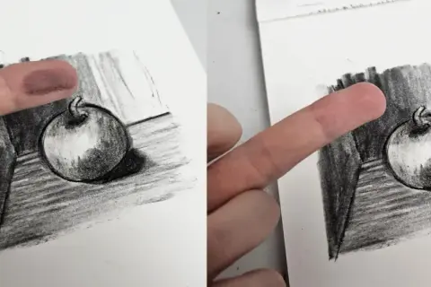 Un doigt est utilisé pour estomper un dessin au fusain d'une pomme, technique d'un artiste connu.