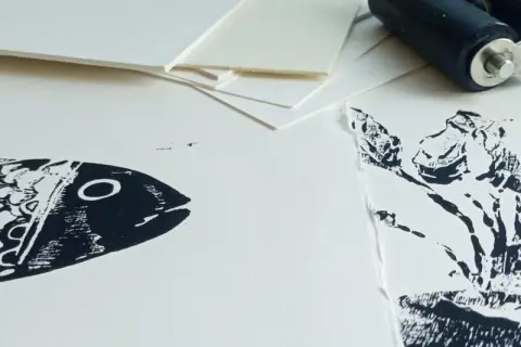 Poisson et plante en impression sur papier Canson. Un rouleau d'encrage est visible en arrière-plan, prêt pour une nouvelle création.