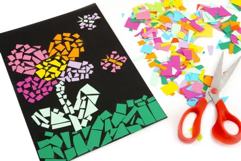 Un collage papier de soie coloré représente des fleurs sur fond noir, à côté de ciseaux et de chutes de papier.