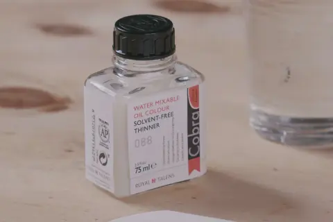 Bouteille de diluant Cobra pour peinture acrylique à base d'eau, sur fond de bois.
