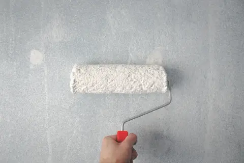 Main tenant, voici comment faire la peinture : un rouleau blanc couvre un mur bleu clair.