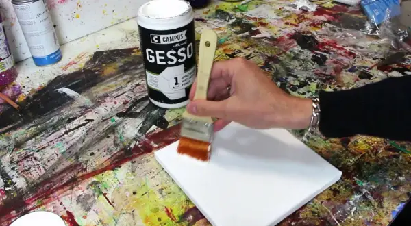Préparation d'une toile pour peindre. On utilise un pinceau pour mélanger gesso et peinture acrylique, créant une base parfaite pour l'art.