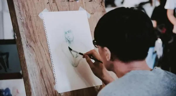 Un artiste réalise une aquarelle personnage facile sur un chevalet en bois. Le croquis est en cours de finition.