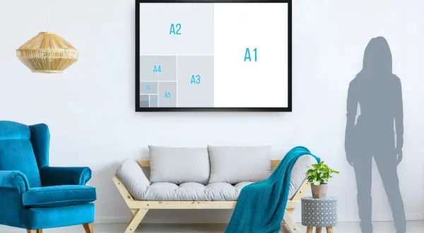 Un salon moderne avec un fauteuil bleu vif, un canapé en bois et un plaid turquoise. Un cadre mural illustre les tailles de papier, montrant que A5 est plus petit que A4.