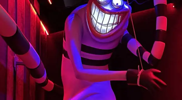 Personnage étrange au sourire démesuré, rappelant un dessin Tim Burton facile. Rayures noires et blanches, lumières rouges et bleues.