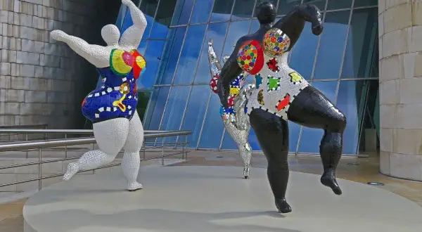 Trois sculptures colorées de Niki de Saint Phalle, des Nanass, dansent joyeusement devant le musée Guggenheim.