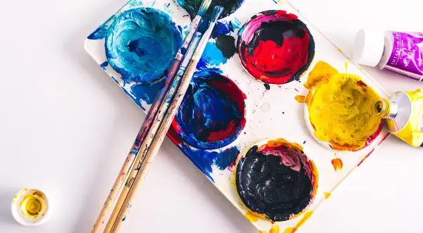 Palette de peinture avec des couleurs vives, des pinceaux et des tubes de peinture. La composition du papier est prête pour une nouvelle création artistique.