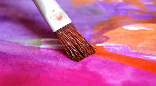 Un pinceau éventail en action, créant des touches de couleur vibrantes sur une œuvre d'art abstraite. Son utilisation est parfaite pour des dégradés doux.
