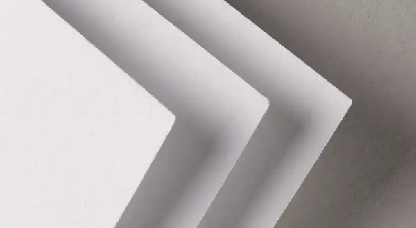 Trois feuilles de papier blanc superposées, créant un effet d'escalier. La texture du papier rappelle celle d'un **format raisin** pour une œuvre d'art.