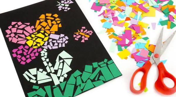 Un collage papier de soie coloré représente des fleurs sur fond noir, à côté de ciseaux et de chutes de papier.