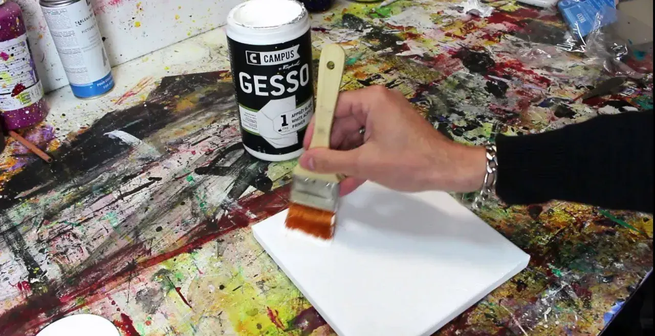 Préparation d'une toile pour peindre. On utilise un pinceau pour mélanger gesso et peinture acrylique, créant une base parfaite pour l'art.