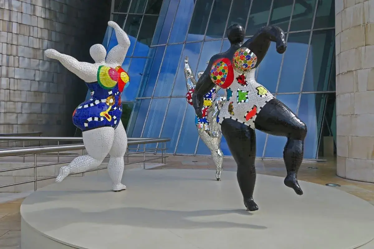 Trois sculptures colorées de Niki de Saint Phalle, des Nanass, dansent joyeusement devant le musée Guggenheim.