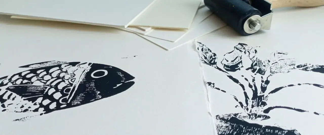 Poisson et plante en impression sur papier Canson. Un rouleau d'encrage est visible en arrière-plan, prêt pour une nouvelle création.