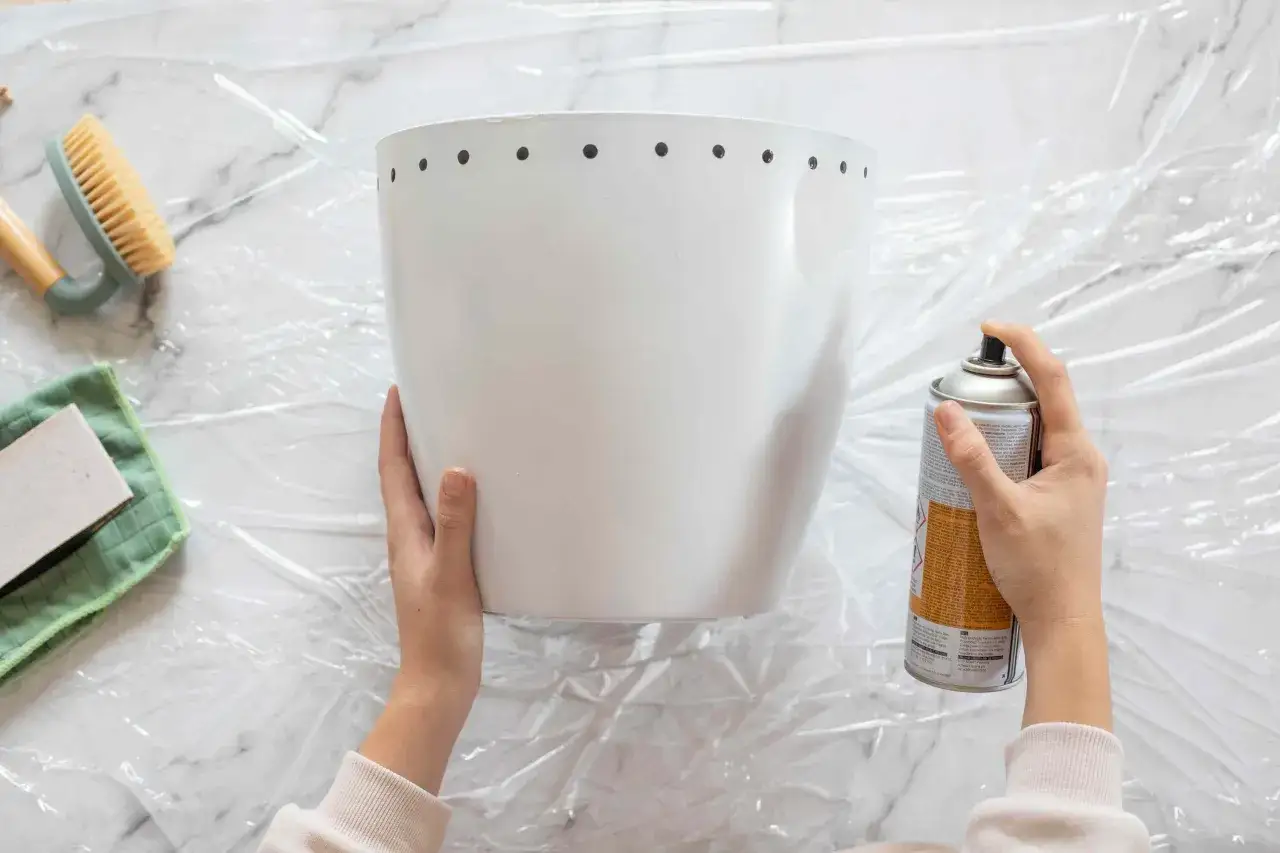 Application de peinture pour plastique sur un pot blanc. Un pinceau et un chiffon sont &agrave; proximit&eacute;.