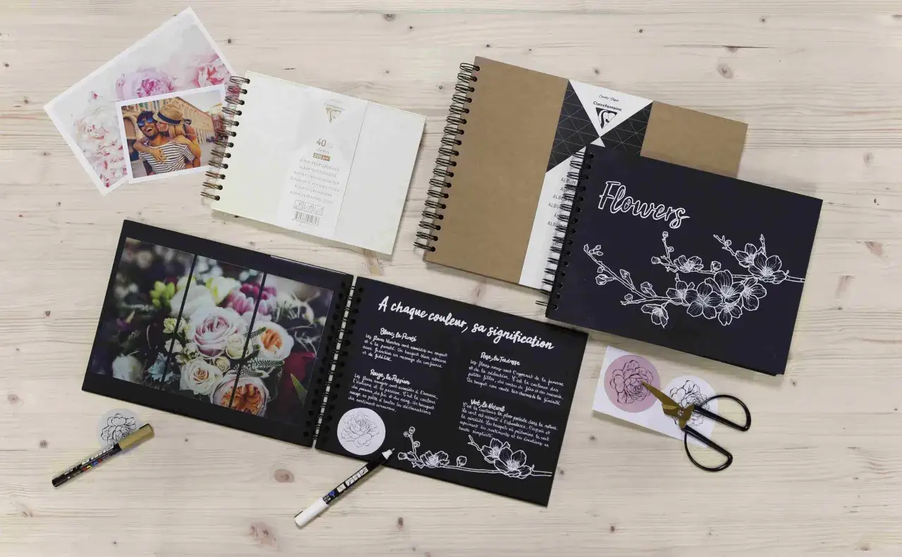 Albums photo, photos de couple et de fleurs, stylos et ciseaux sur fond de bois. Une id&eacute;e art cr&eacute;atif pour vos souvenirs.