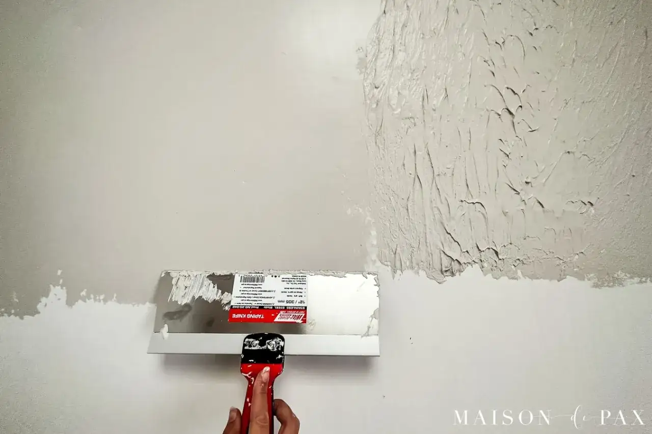 Application d'enduit textur&eacute; sur un mur avec une spatule. Apprenez comment faire la peinture pour un effet d&eacute;coratif.