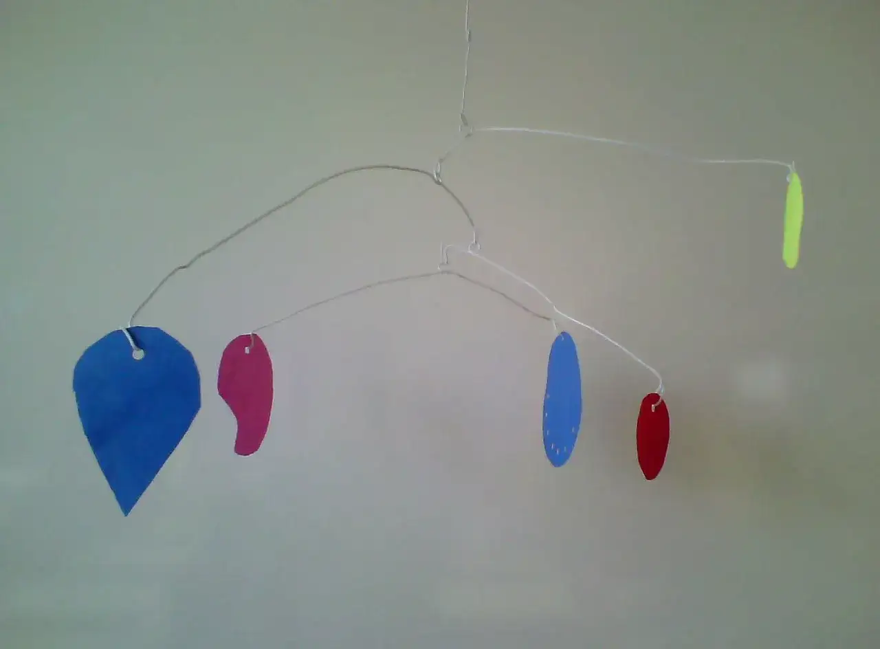 Mobile Calder maternelle aux formes color&eacute;es : un c&oelig;ur bleu, des gouttes roses et bleues, et une forme jaune.