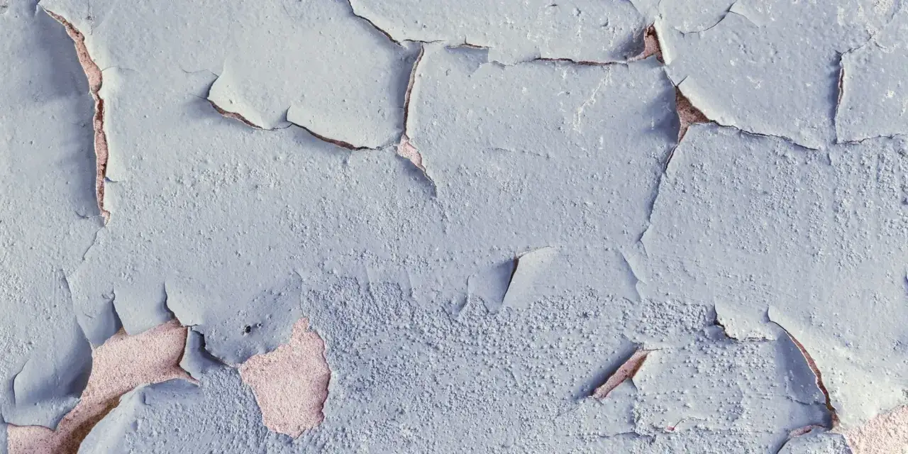 Texture d'un mur o&ugrave; la peinture qui ne tient pas s'&eacute;caille, r&eacute;v&eacute;lant la couche inf&eacute;rieure ros&eacute;e.