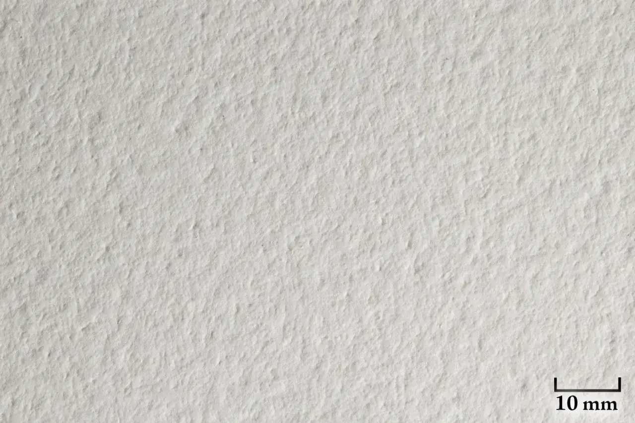 Texture d&eacute;taill&eacute;e d'une impression sur papier Canson blanc, r&eacute;v&eacute;lant la granulation subtile du support. Une r&egrave;gle de 10 mm est visible.