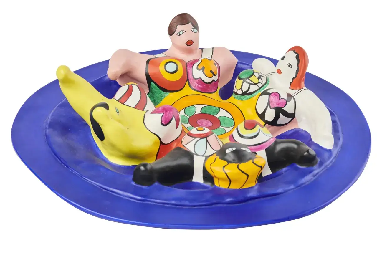 Assiette bleue orn&eacute;e de joyeuses Nanas color&eacute;es de Niki de Saint Phalle, un festin visuel plein de vie.