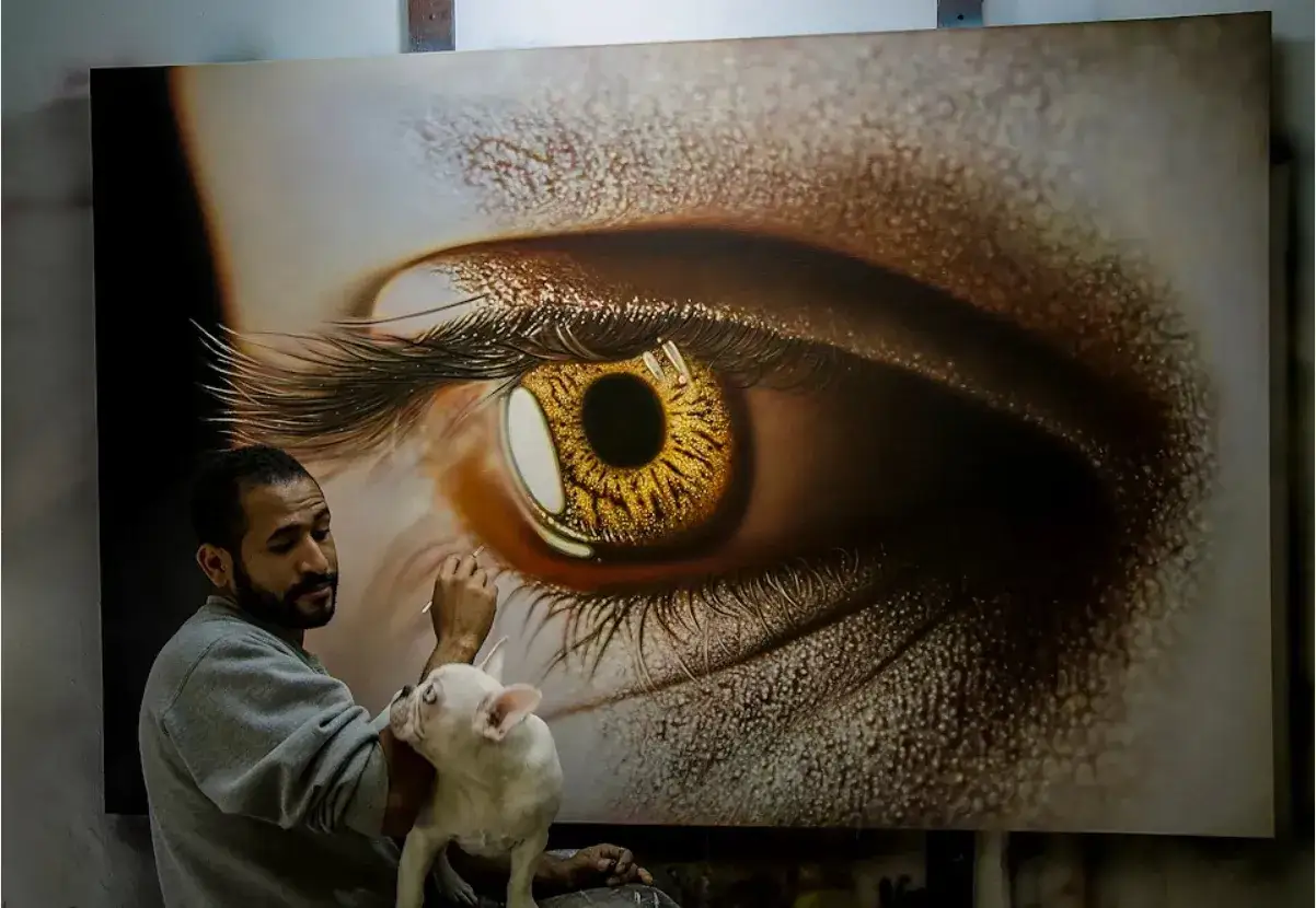 Un peintre hyperr&eacute;aliste fran&ccedil;ais travaille sur un &oelig;il dor&eacute; saisissant, son bouledogue fran&ccedil;ais curieux observant.