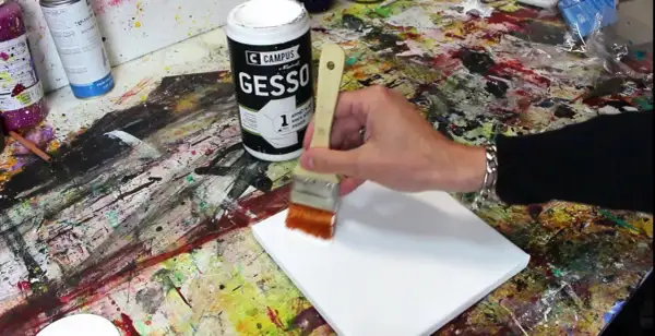 Préparation d'une toile pour peindre. On utilise un pinceau pour mélanger gesso et peinture acrylique, créant une base parfaite pour l'art.