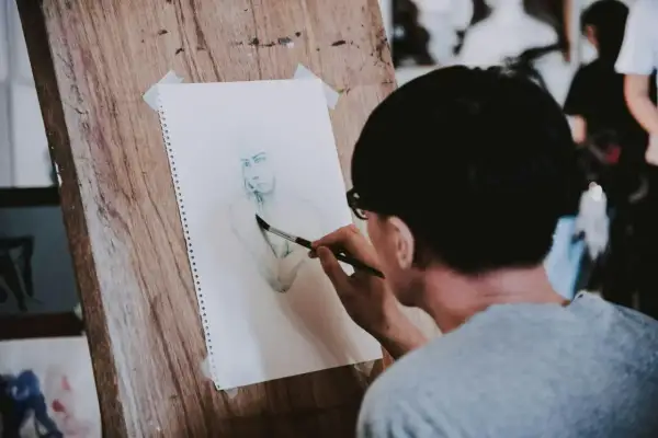 Un artiste réalise une aquarelle personnage facile sur un chevalet en bois. Le croquis est en cours de finition.