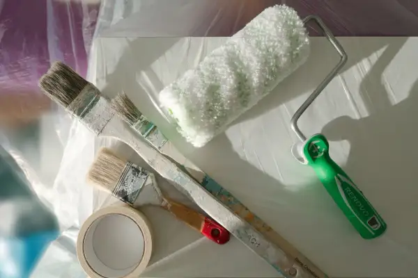 Pinceaux et rouleau de peinture acrylique prêts à nettoyer. Une bande de masquage est aussi visible.