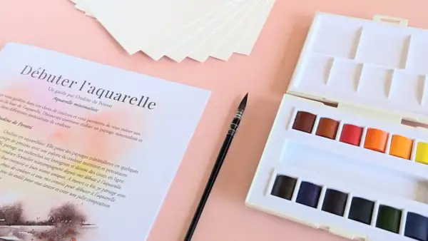 Kit de matériel peinture aquarelle : palette de couleurs vives, pinceau fin et papier texturé pour débuter.