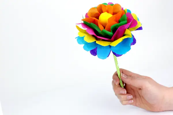 Une fleur en papier Canson facile, aux couleurs vives, tenue par une main.