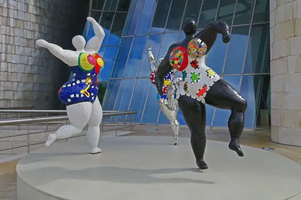 Trois sculptures colorées de Niki de Saint Phalle, des Nanass, dansent joyeusement devant le musée Guggenheim.