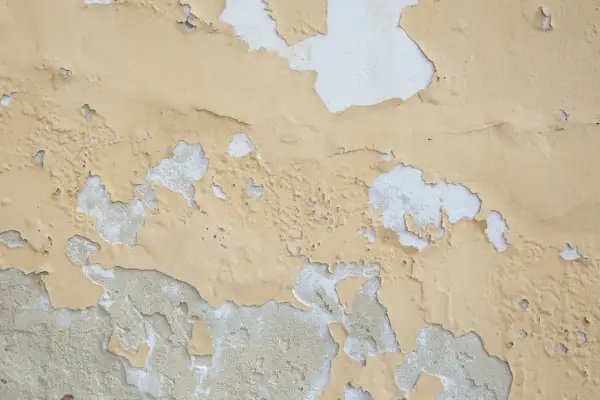 Texture d'un mur où la peinture qui ne tient pas s'écaille, révélant le plâtre blanc en dessous.