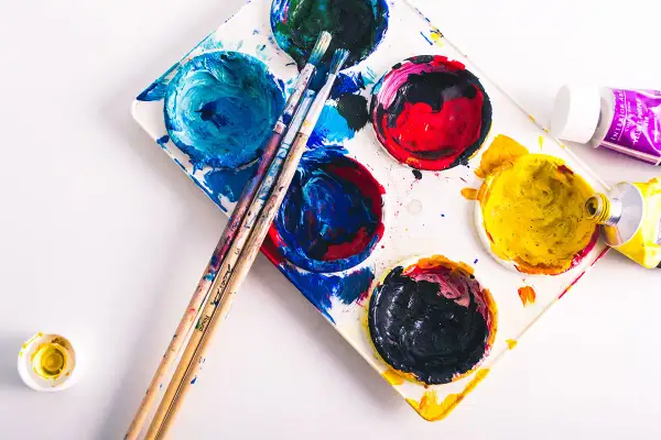 Palette de peinture avec des couleurs vives, des pinceaux et des tubes de peinture. La composition du papier est prête pour une nouvelle création artistique.